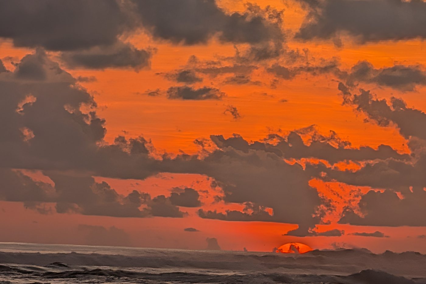The sun dropping into the Pacific behind a bank of cloud