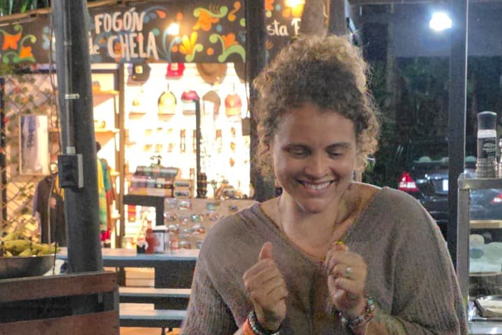 Tasha laughing over a pan of empanadas at El Fogón de Chela, Costa Rican flags strung overhead