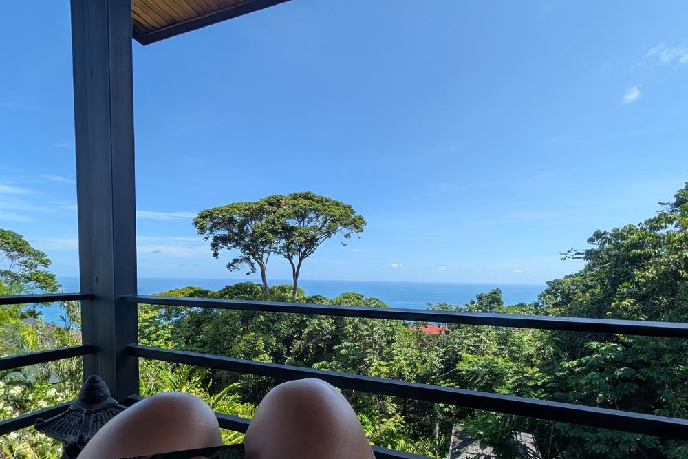 Bare feet up on the balcony rail at Pagoda del Loto Azul, a book in hand, rainforest and the Pacific beyond