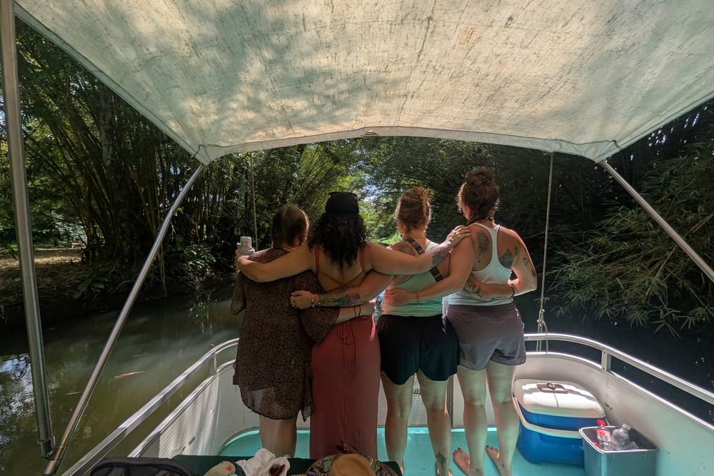 Four friends arm in arm at the bow of the boat, looking out over the Sierpe River