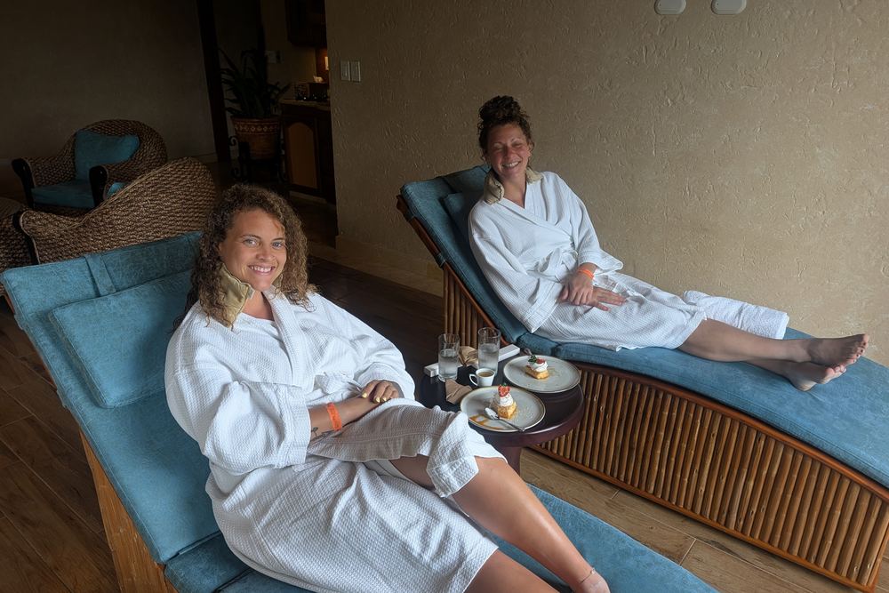 Two loungers in white robes on the spa terrace at The Springs, coffee and dessert on a small table between them