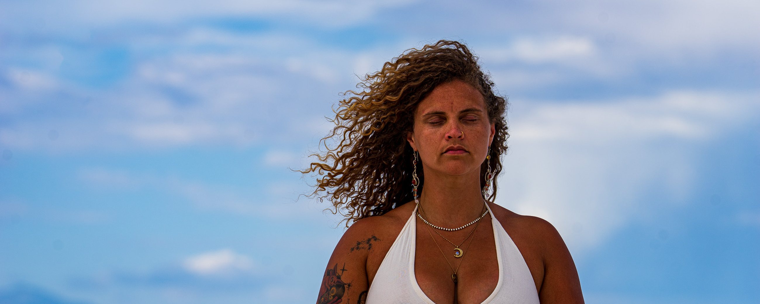 Tasha seated in meditation on white sand under a wide sky