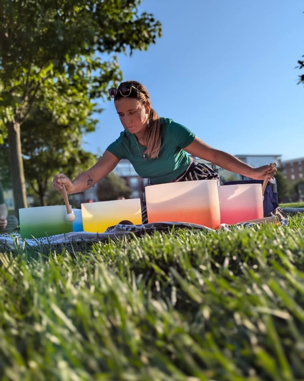 Kylie Davis laying out crystal singing bowls in a park before an outdoor sound journey