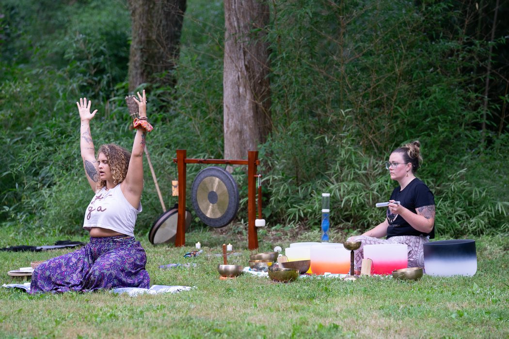 A small circle gathered around a gong and bowls in a park