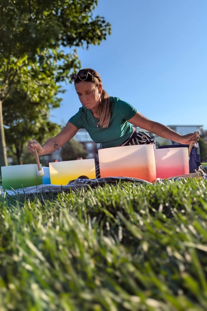 Kylie setting out coloured crystal bowls on the grass before a group sound bath
