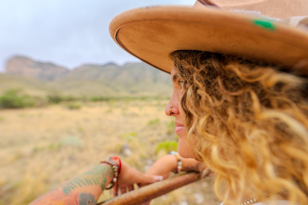 Tasha in a wide-brimmed hat looking out over open country