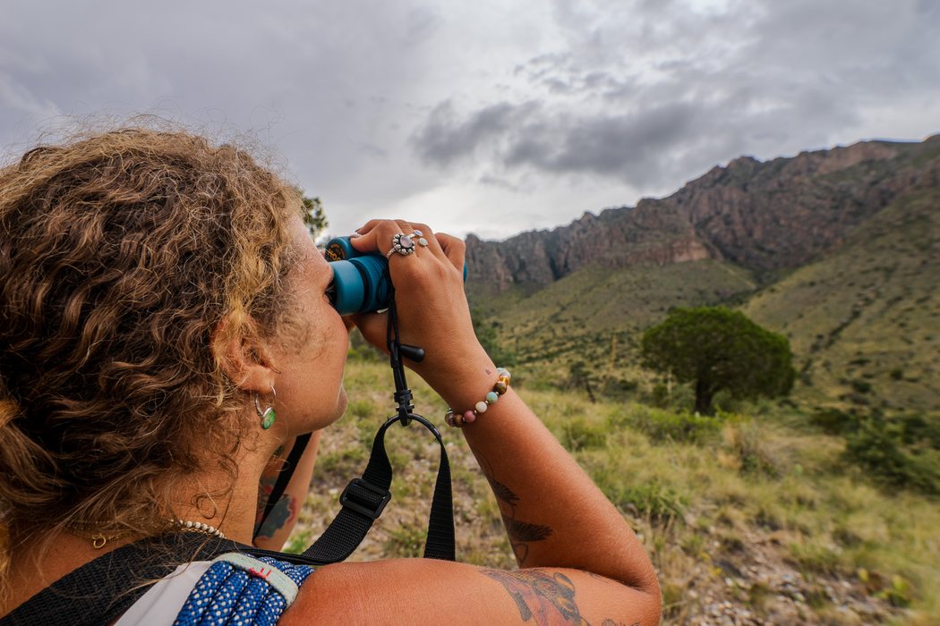 Tasha looking out through binoculars toward a mountain range