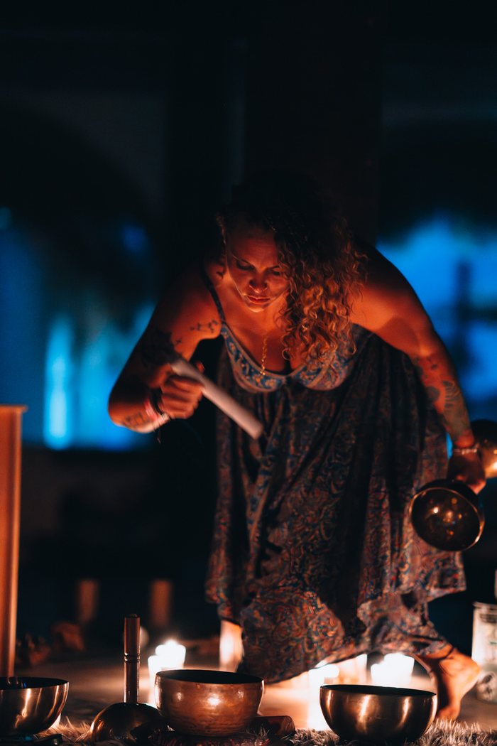 Tasha playing a crystal bowl in blue light at a monthly sound journey