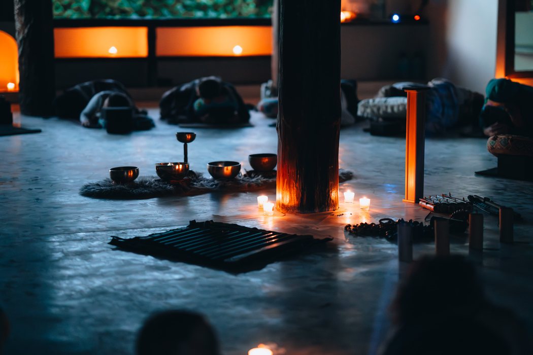 A room laid out with candles and bowls before an evening sound bath