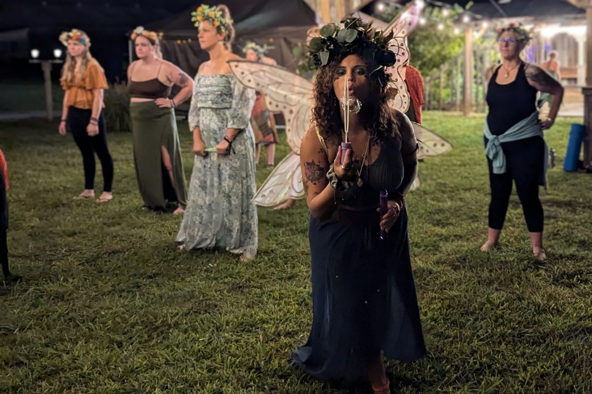 A gathering on the grass at dusk under strings of lights