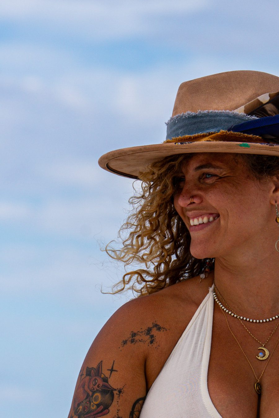 Tasha laughing in a wide-brimmed hat against an open sky