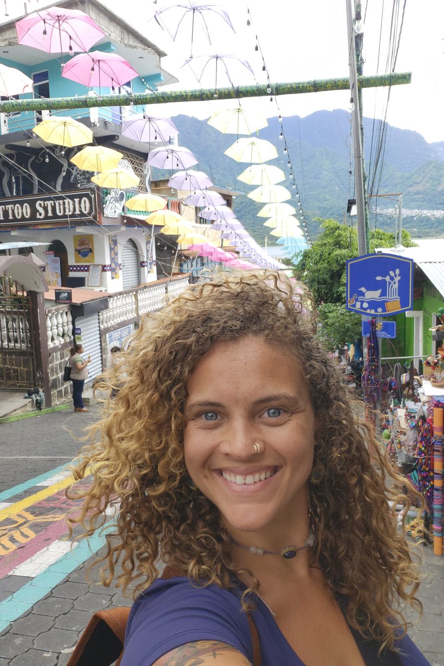 Tasha smiling in a street market under a canopy of coloured umbrellas