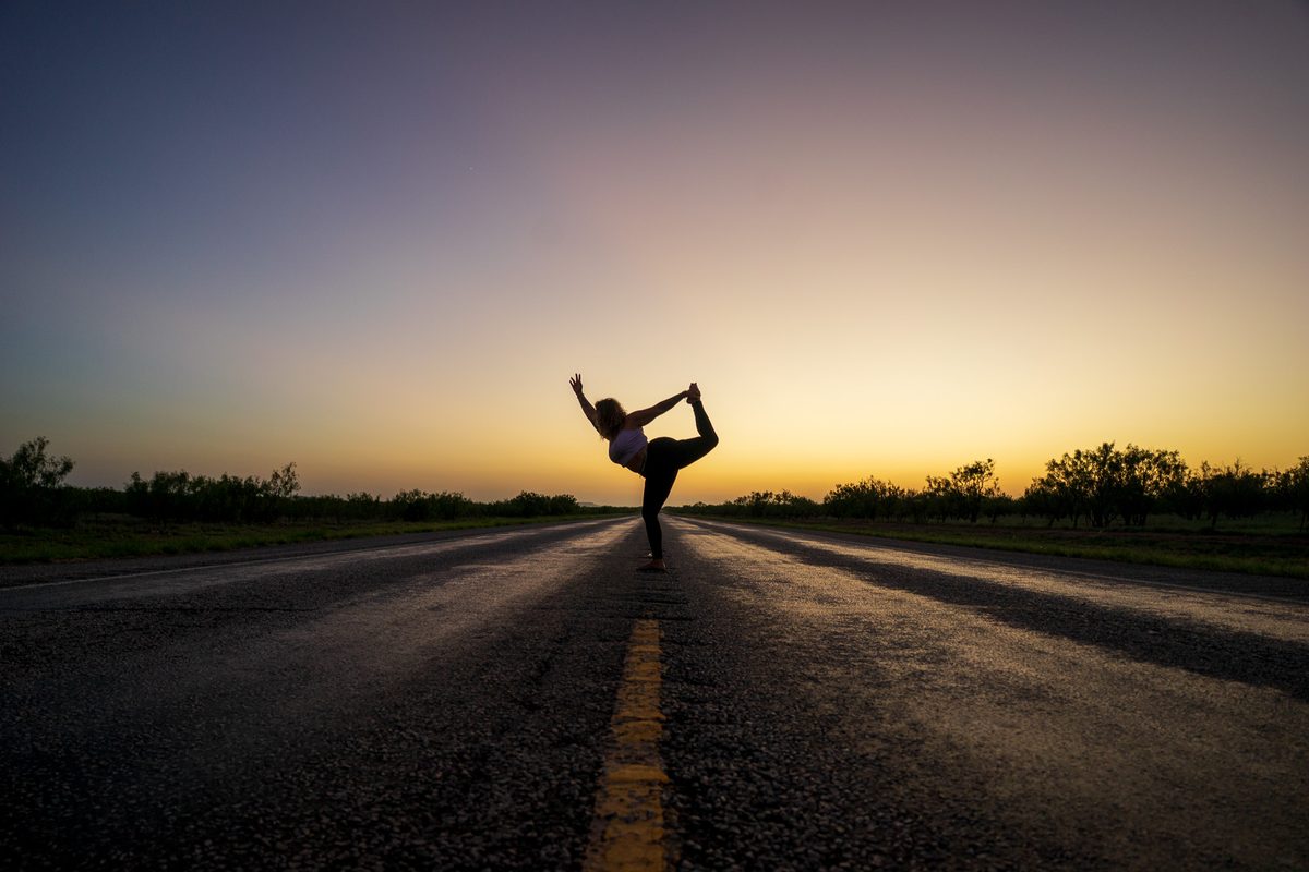 Tasha in dancer pose on an empty road at sunset