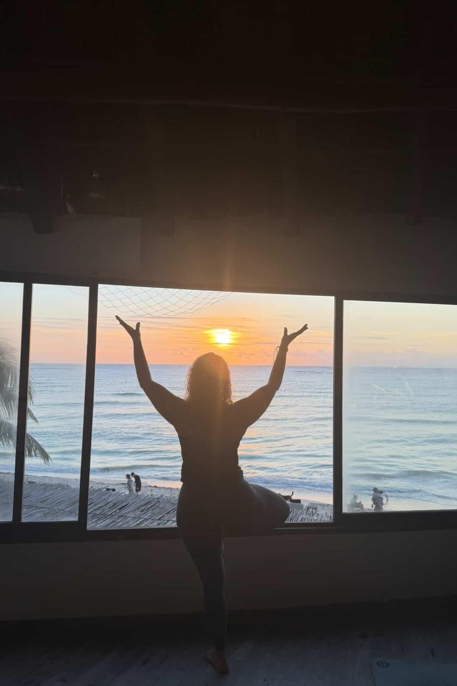 A silhouette in tree pose against the sunrise over the ocean
